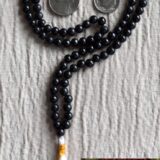 A Black Onyx mala necklace with 108 hand-knotted beads, designed for grounding and protection. Ideal for meditation, featuring smooth, polished onyx beads associated with the Root Chakra and the zodiac signs Capricorn and Leo.