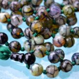 Dragon Vein Agate Mala Necklace with 108 hand-knotted beads, designed to activate the Root and Sacral Chakras. Promotes grounding and enhances creativity, perfect for Aries and Gemini.