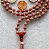 Faceted Rhodonite Mala Necklace with 108 hand-knotted beads, designed to balance the Heart and Root Chakras. Promotes love, compassion, and emotional healing, ideal for Taurus and Leo.