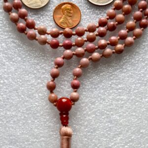 Faceted Rhodonite Mala Necklace with 108 hand-knotted beads, designed to balance the Heart and Root Chakras. Promotes love, compassion, and emotional healing, ideal for Taurus and Leo.