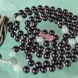 A tactile Black Tourmaline & Aventurine Mala Necklace with 108 smooth beads plus 1 central guru bead. Designed to support the Root and Heart Chakras, it resonates with Capricorn and Virgo, offering protection, prosperity, and emotional healing. Handcrafted for quality and comfort, ideal for meditation.