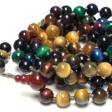 Powerful Tiger's Eye Mala Beads Necklace featuring a mix of blue, black, grey, green, miracle, purple, red, brown, and golden beads, designed for Throat and Root Chakra activation, strength, and protection, associated with Gemini and Capricorn.