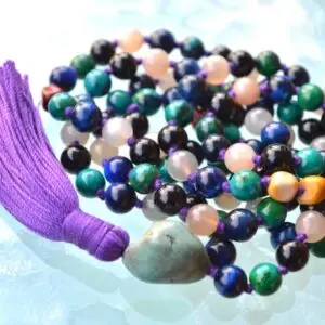 A Third Eye Chakra Mala Necklace featuring 108 beads plus 1 guru bead. This necklace supports the Third Eye Chakra with stones like Turquoise, Blue Tiger Eye, Moonstone, Black Onyx, Chrysocolla, and Mookaite. Handcrafted for durability, it enhances intuition and insight. Suitable for meditation and spiritual practice.