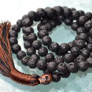 A Raven Skull Lava Mala Beads Necklace featuring 108 hand-knotted lava beads, with a striking raven skull centerpiece, designed for protection, transformation, and grounding, resonating with Scorpio and Capricorn signs.