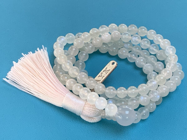 A handcrafted Rainbow Moonstone Mala Necklace with 108 beads, designed to align the Crown and Third Eye chakras, offering balance and emotional healing.