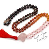 A Red Jasper, Garnet, Smoky Quartz, Rose Quartz, Carnelian Mala Beads Necklace with 108 beads plus 1 guru bead. This necklace supports the Root and Heart Chakras, resonates with Aries and Scorpio, and promotes vitality and emotional healing. Handcrafted for quality and comfort, suitable for meditation and spiritual practice.