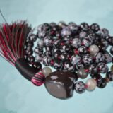 A handcrafted Snowflake Obsidian Mala Necklace with 108 beads, designed for protection and balance, resonating with the Root Chakra and associated with Scorpio.