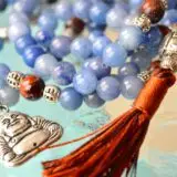 A Blue Aventurine & Buddha Charm Mala Beads Necklace featuring genuine blue aventurine beads, a Buddha charm, and connections to the Third Eye and Throat Chakras, with associations to Libra and Virgo, designed for inner peace and spiritual wisdom.