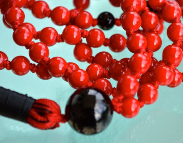 Red Coral & Black Onyx Mala Necklace featuring 108 hand-knotted beads, designed to enhance courage and protection. Ideal for meditation and spiritual practices, aligning with the Root and Sacral Chakras, and resonating with Aries and Capricorn.