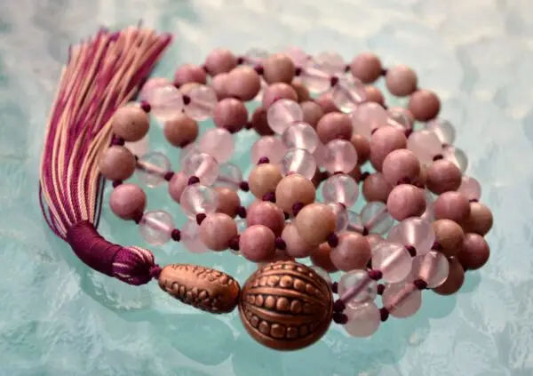 A Rose Quartz & Rhodonite Mala Necklace featuring beads designed to enhance emotional healing, self-love, and balance the Heart Chakra, associated with the zodiac signs Libra and Taurus.