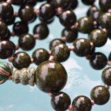 Serpentine Hand Knotted Mala Necklace featuring 108 hand-knotted Serpentine beads, designed to enhance healing and spiritual awakening. Ideal for meditation and spiritual practices, aligning with the Heart and Crown Chakras, and resonating with Gemini and Sagittarius.