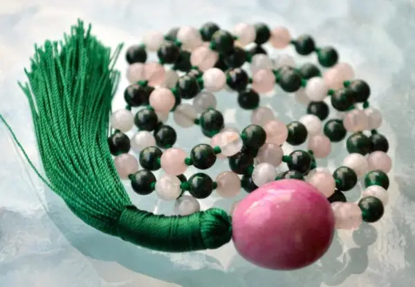 A Rose Quartz, Moonstone, and Malachite Mala Necklace featuring 108 beads plus 1 guru bead. This necklace supports the Heart and Third Eye Chakras, resonating with Taurus and Cancer, promoting love, intuition, and transformation. Handcrafted, it’s ideal for meditation and spiritual practice.