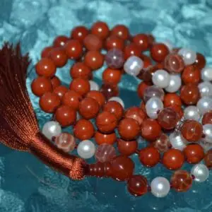 A Red Jasper Mala Necklace with fire agate and pearl beads, featuring 108 mala beads, associated with the Root Chakra, designed for Aries zodiac signs, promoting vitality and courage.