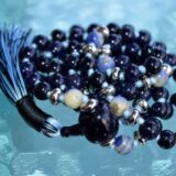 Galaxy Stone Blue Goldstone Mala Necklace featuring shimmering Blue Goldstone beads, hand-knotted, associated with Root and Throat Chakras for ambition and protection, aligned with Sagittarius.