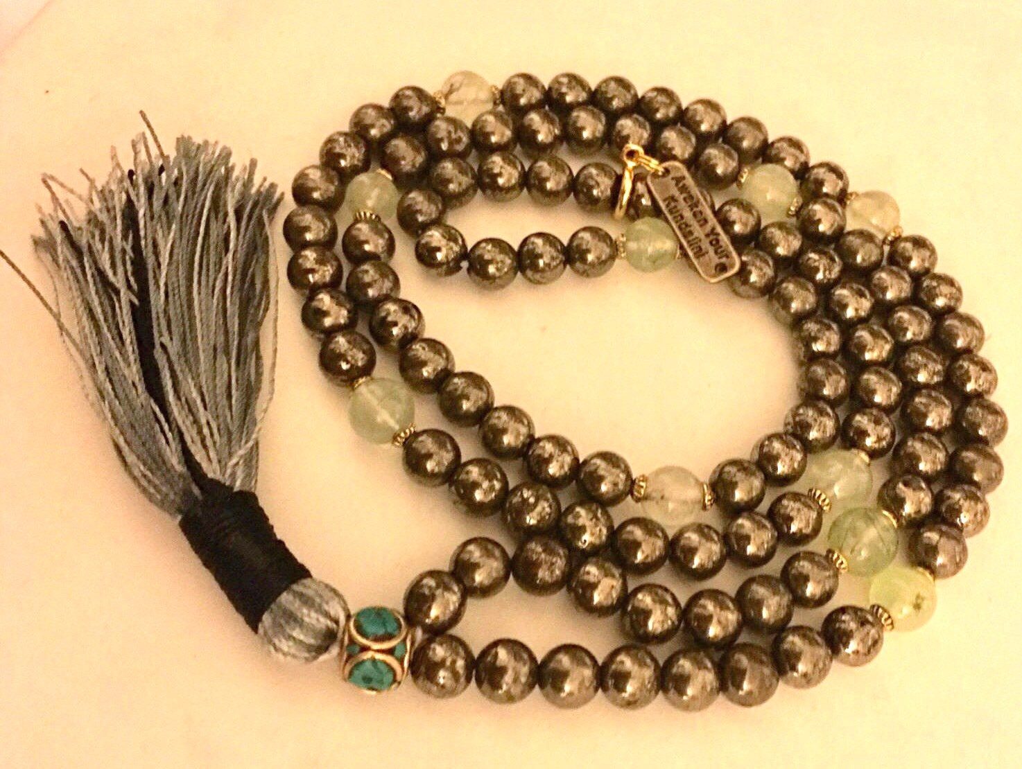 A Pyrite & Prehnite Mala Necklace with 108 hand-knotted beads, designed to boost confidence and healing, aligned with Solar Plexus and Heart Chakras, and ideal for Leo, Virgo, and Capricorn.