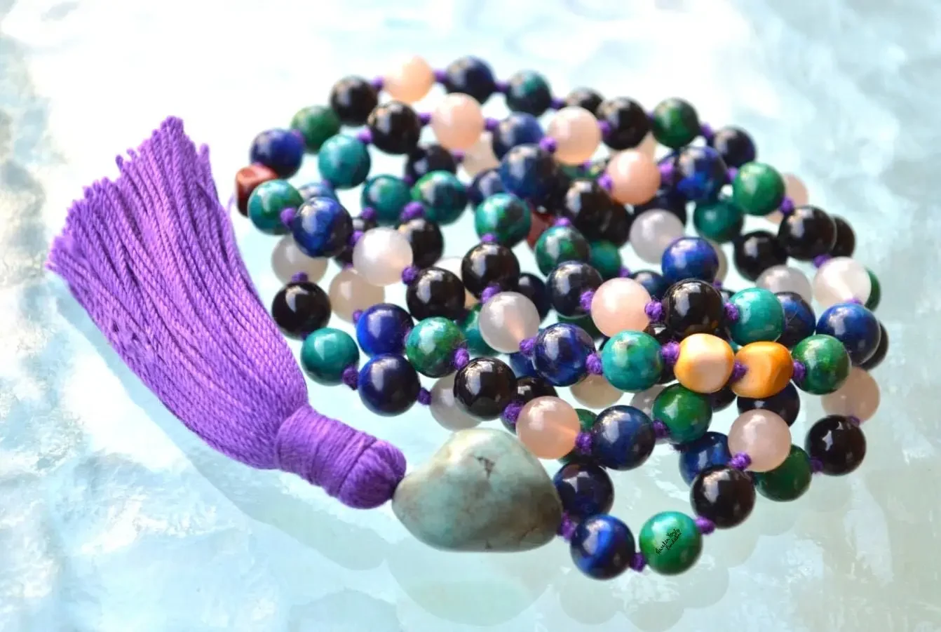 A Third Eye Chakra Mala Necklace featuring 108 beads plus 1 guru bead. This necklace supports the Third Eye Chakra with stones like Turquoise, Blue Tiger Eye, Moonstone, Black Onyx, Chrysocolla, and Mookaite. Handcrafted for durability, it enhances intuition and insight. Suitable for meditation and spiritual practice.