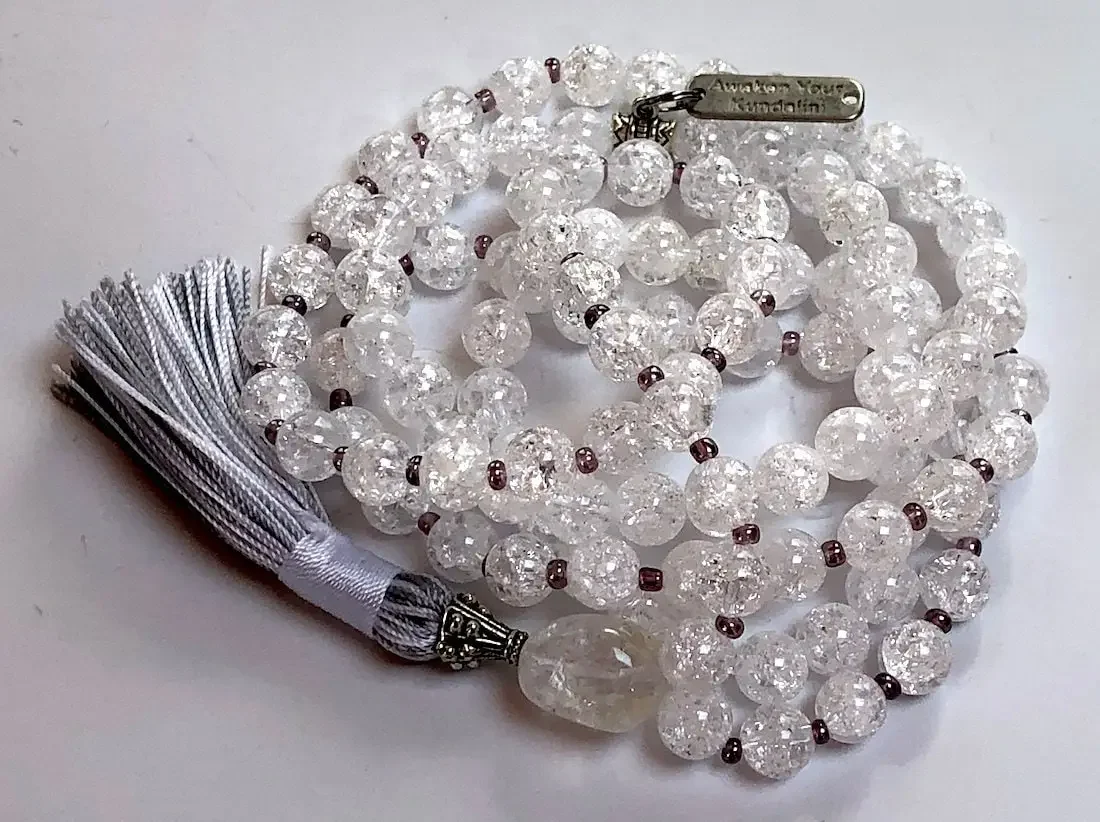 A Himalayan Crackled Quartz Mala Necklace featuring smooth, authentic crackled quartz beads in a clear, textured finish. The necklace is hand-knotted between each bead for durability and is finished with a beautifully crafted tassel. It supports the Crown Chakra, promoting clarity and transformation.