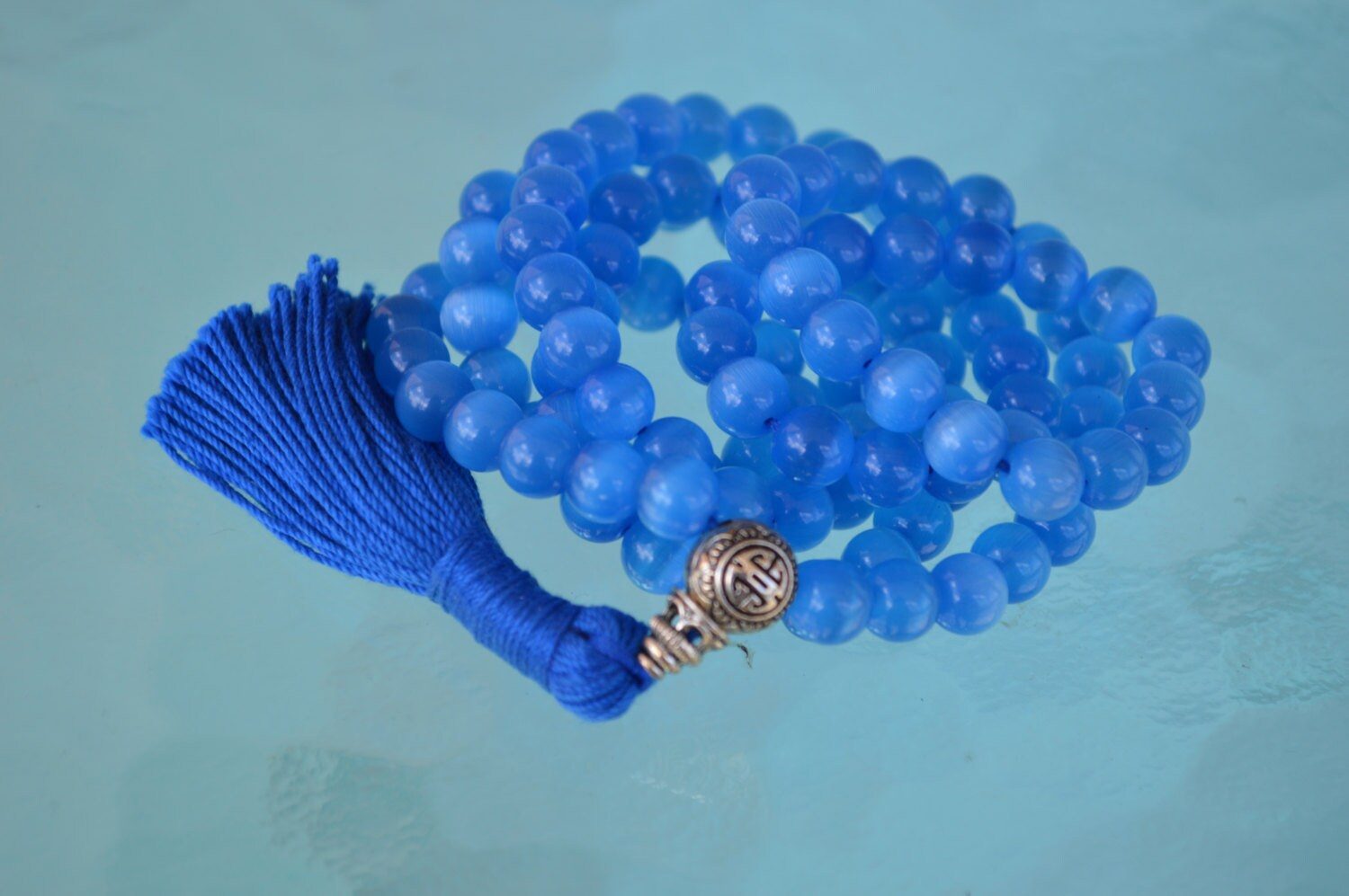 A Blue Cat's Eye Beads Mala Necklace designed for Throat Chakra alignment, resonating with Gemini and Aquarius energies, enhancing communication and mental clarity.