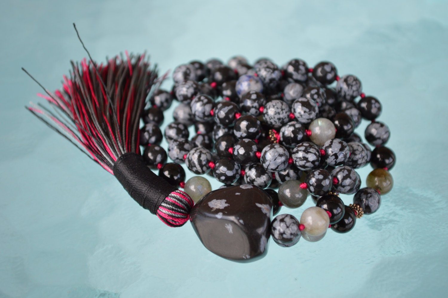 A handcrafted Snowflake Obsidian Mala Necklace with 108 beads, designed for protection and balance, resonating with the Root Chakra and associated with Scorpio.