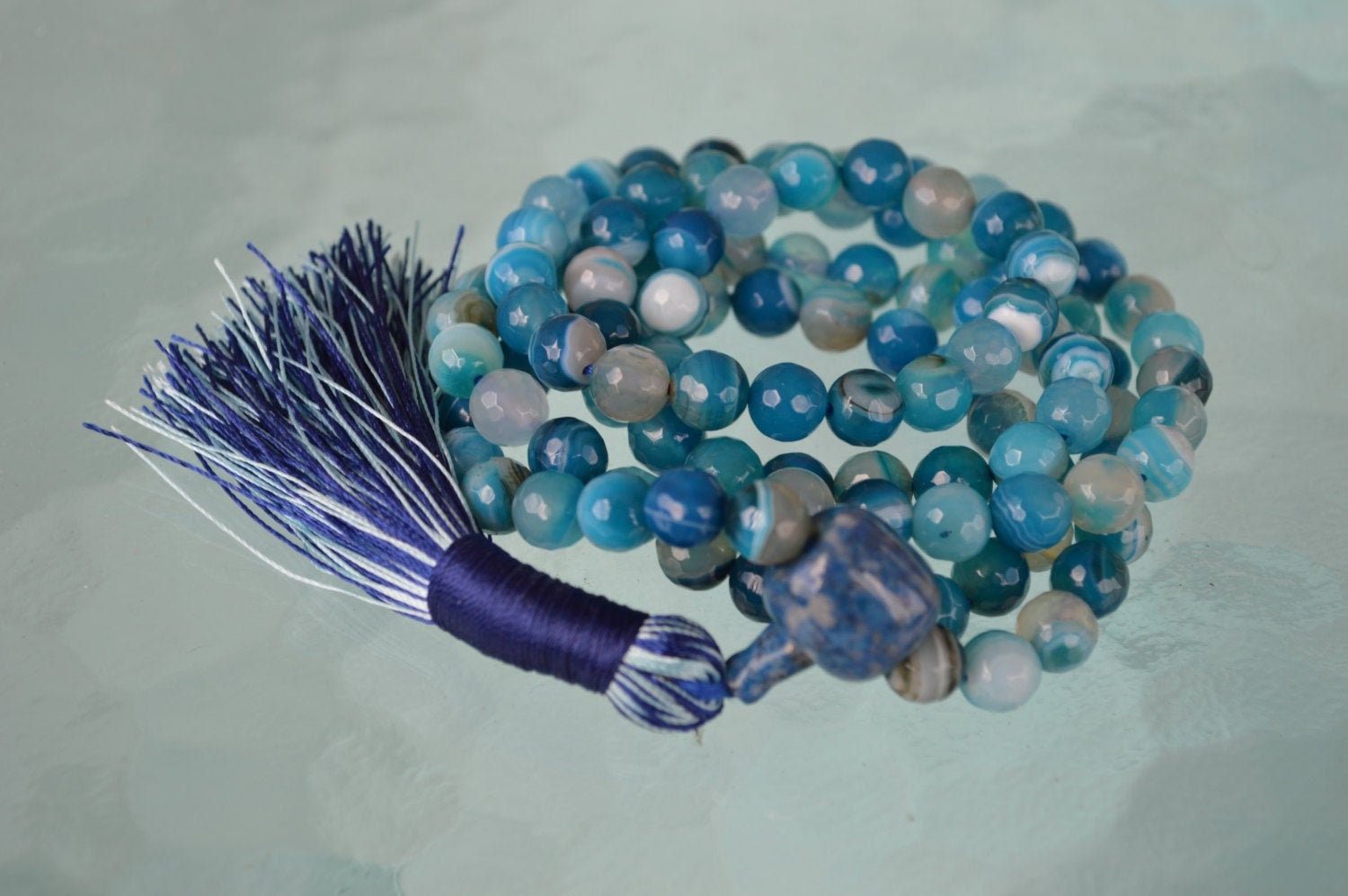 A Blue Crazy Agate Mala Necklace featuring 108 beads plus 1 guru bead. This necklace supports the Throat and Third Eye Chakras, resonates with Gemini and Pisces, and promotes clarity and communication. Handcrafted for quality and comfort, it’s suitable for meditation and spiritual practice.