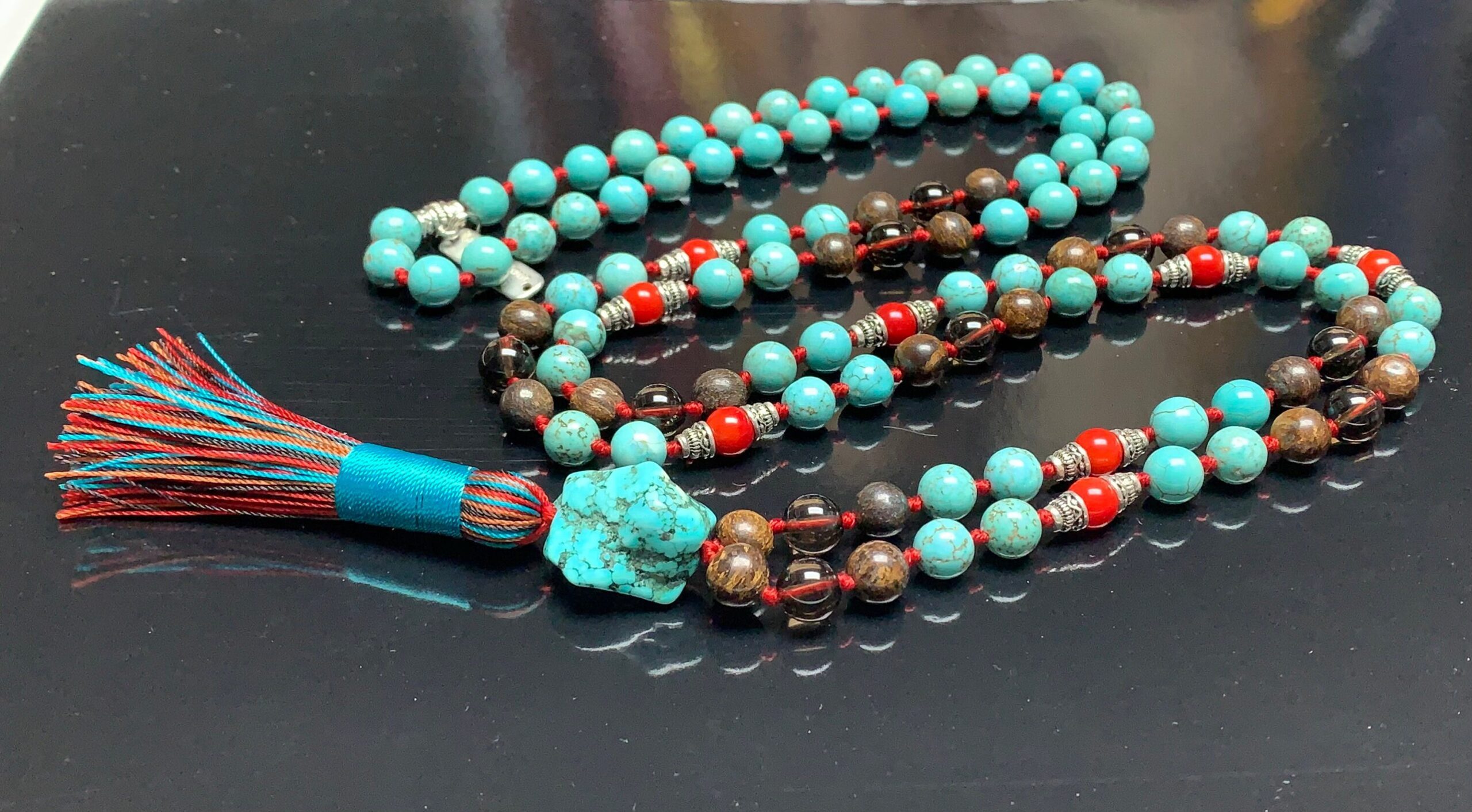 A Turquoise, Bronzite, and Coral Mala Necklace with 108 beads plus 1 guru bead. This necklace supports the Throat, Root, and Sacral Chakras, resonates with Sagittarius and Taurus, and promotes protection, communication, and grounding. Handcrafted for comfort and quality, it’s suitable for meditation and spiritual practice.