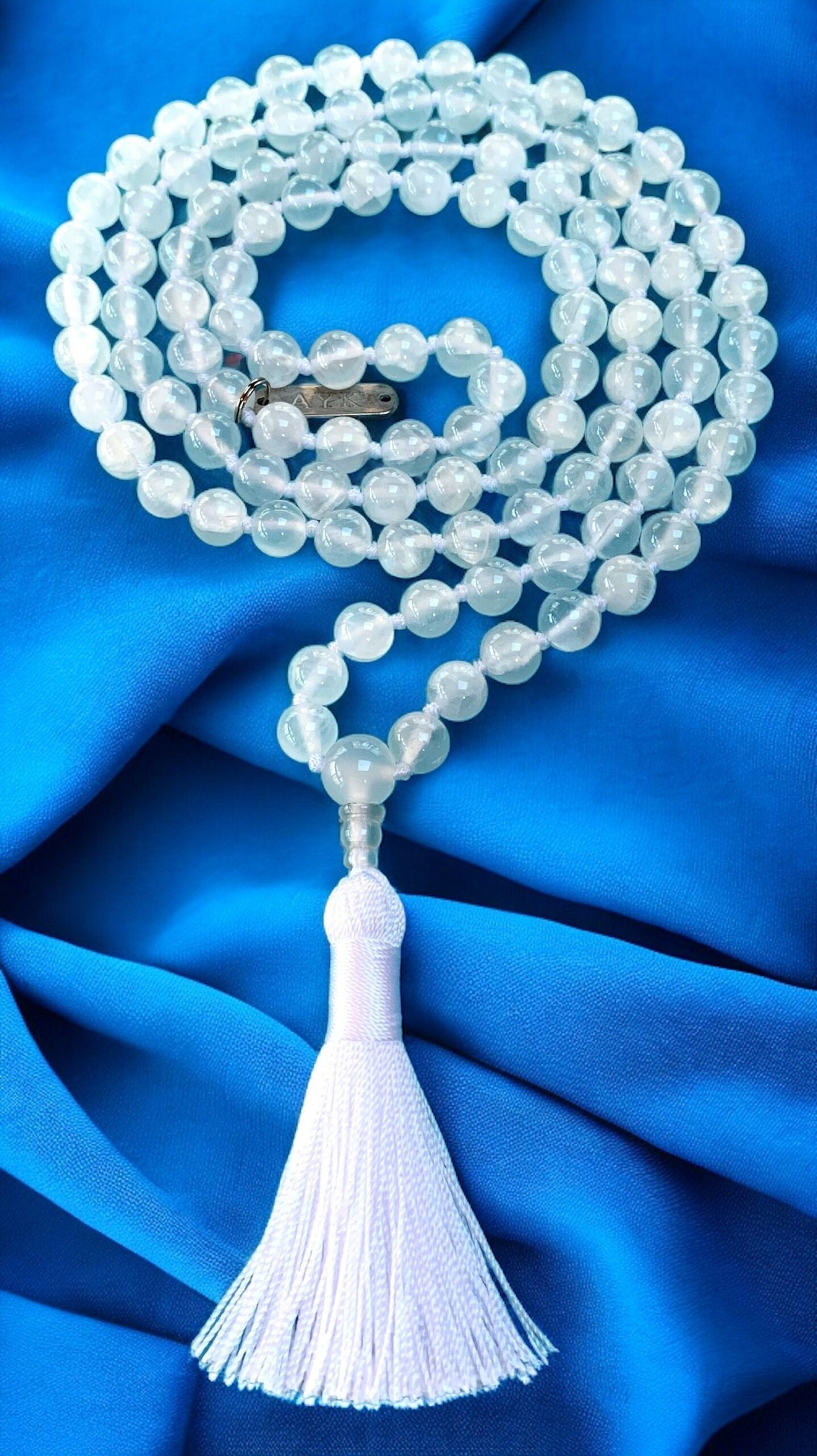 A Selenite Beaded Necklace with 108 beads plus 1 guru bead. This knotted mala supports the Crown Chakra, resonates with Cancer and Pisces, and promotes mental clarity and spiritual growth. Handcrafted for quality and comfort, ideal for meditation and spiritual practice.