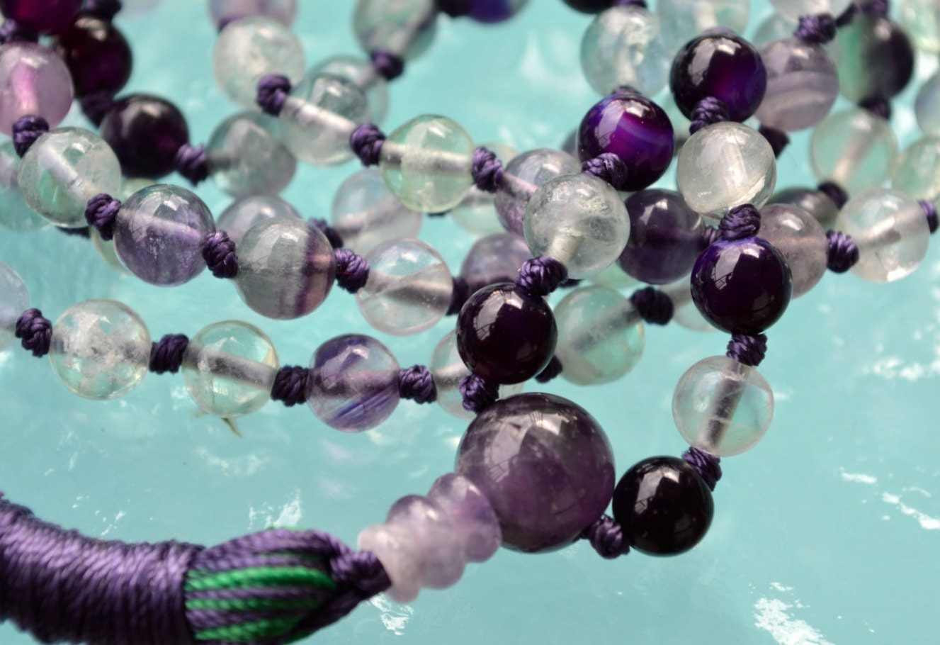 A Rainbow Fluorite Mala Necklace with 108 beads plus 1 guru bead. This necklace supports the Third Eye and Crown Chakras, resonates with Aquarius and Pisces, and enhances intuition and mental clarity. Handcrafted for quality and comfort, ideal for meditation and spiritual practice.