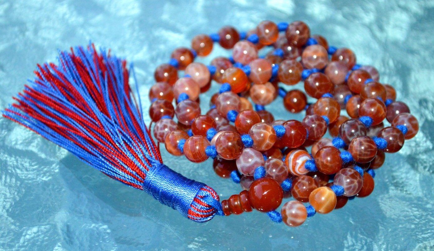 Crackled Fire Agate Mala Necklace featuring 108 hand-knotted Crackled Fire Agate beads, designed for protection and vitality. Ideal for meditation and spiritual practices, aligning with the Root and Sacral Chakras, and resonating with Aries and Scorpio.